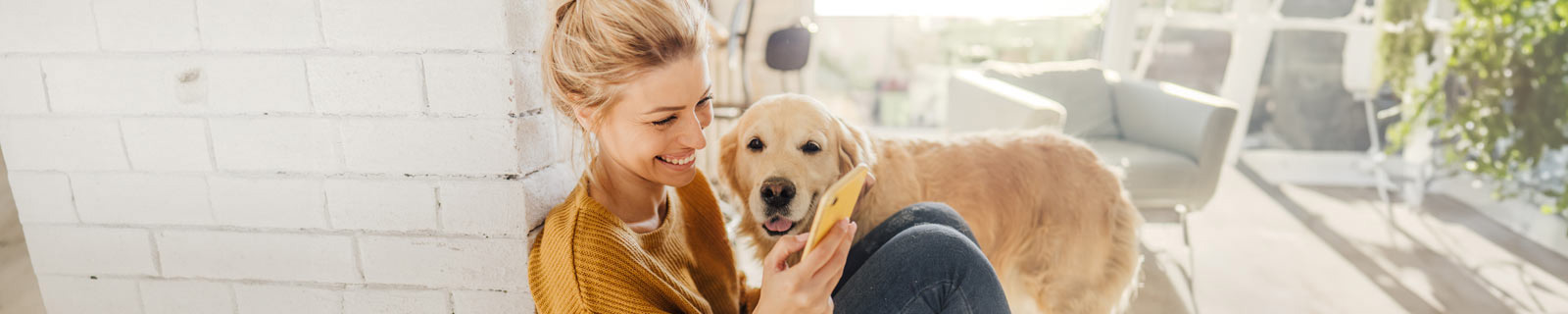 Woman smiling at her phone with a dog