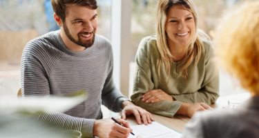 Smiling couple signing a contract for a new home