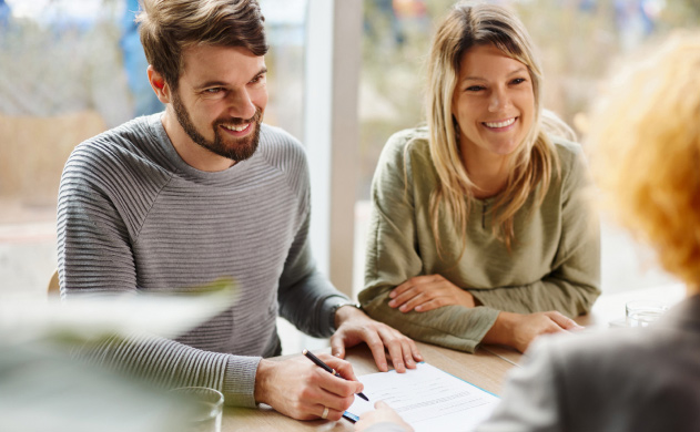 Smiling couple signing a contract for a new home