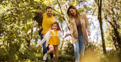 A family wearing yellow skipping through the forest