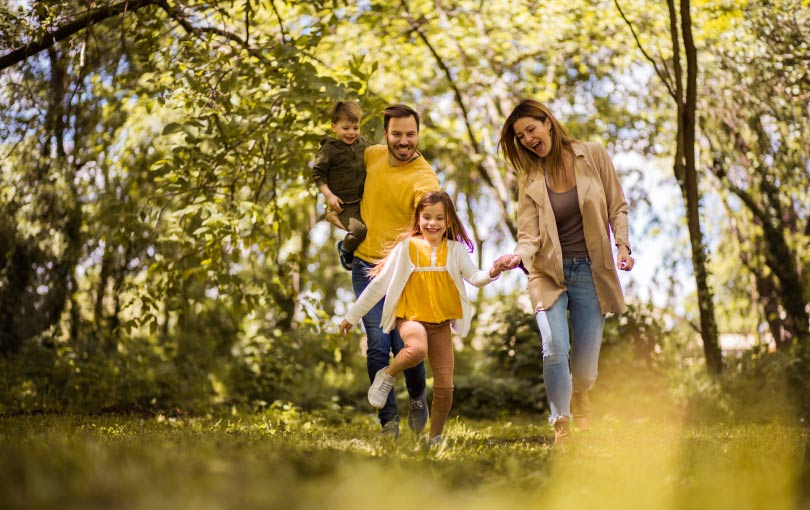 A family wearing yellow skipping through the forest