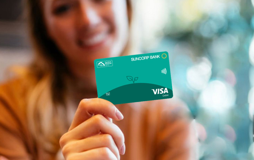 A woman holding a Carbon Neutral Visa Debit card